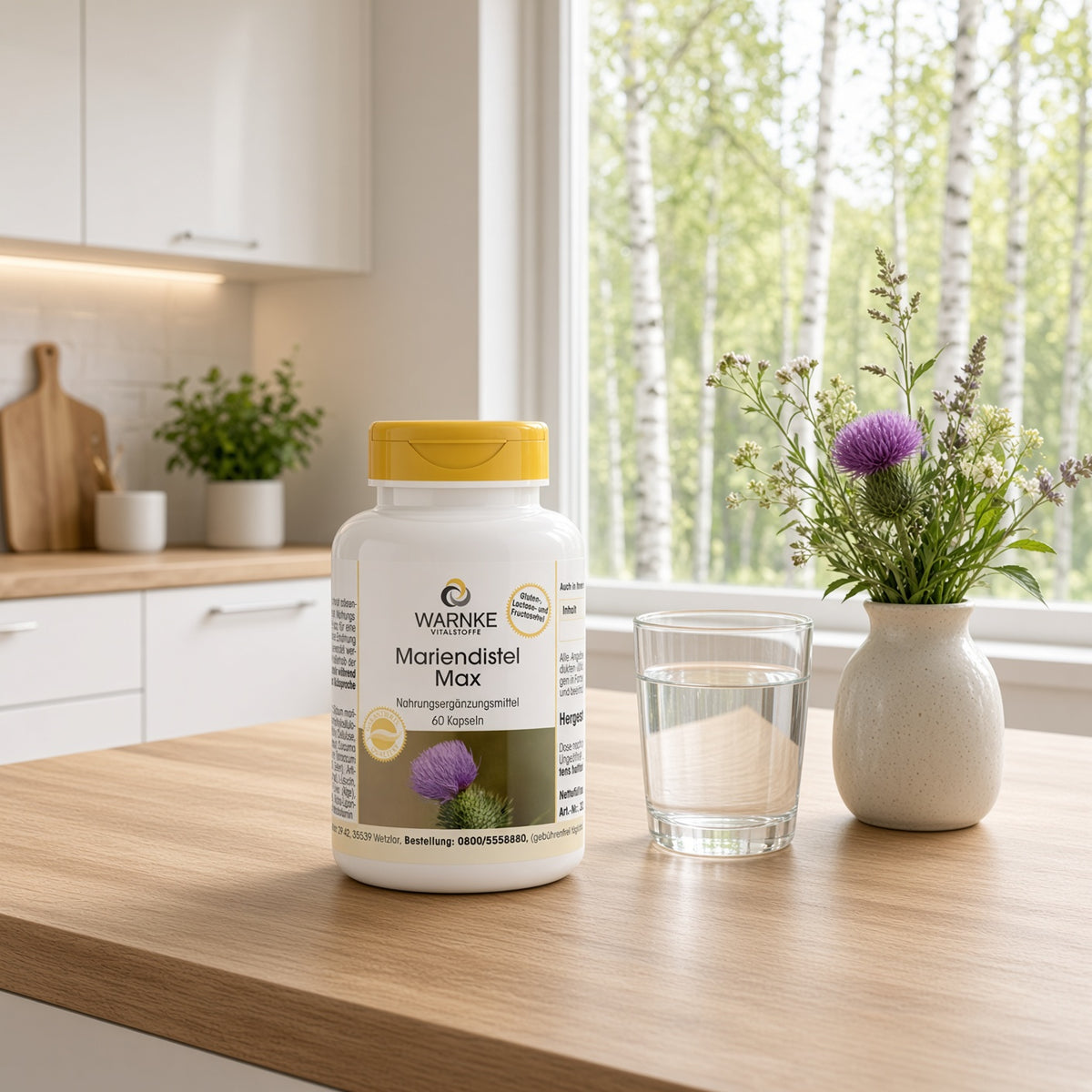 Mariendistel-Max-Flasche mit gelbem Verschluss steht auf einem Holztisch neben einem Glas Wasser und einer Vase mit Blumen.