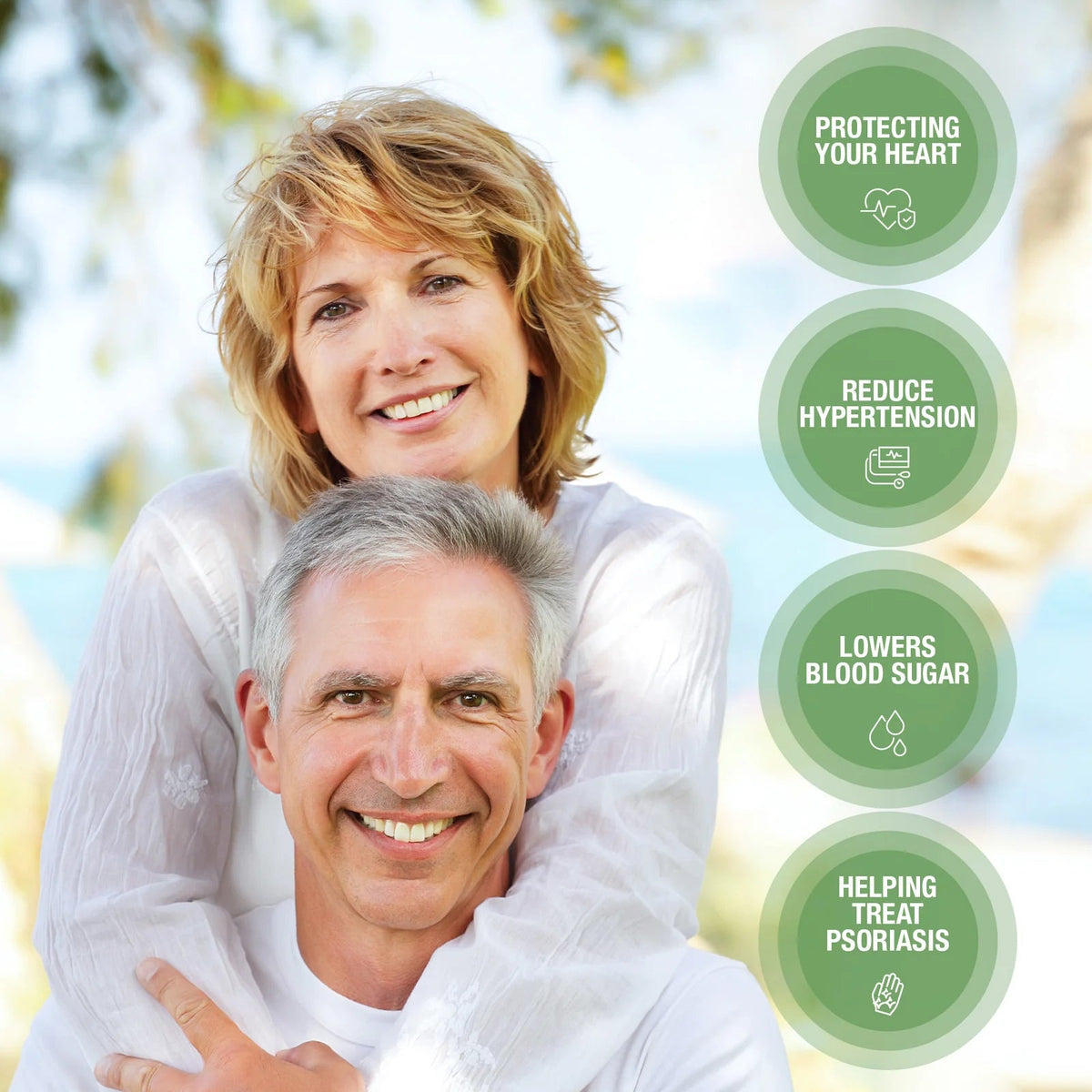 Two people smiling in a natural outdoor environment. The woman has wavy, blonde hair and a white blouse, while the man has gray hair and a white T-shirt.