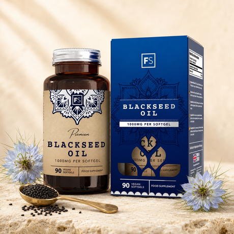 Premium black seed oil in brown glass bottle with silver cap and blue box, surrounded by black seeds and flowers.