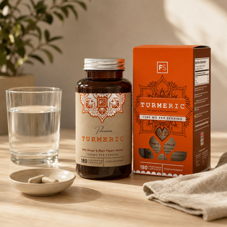 Capsules with turmeric, ginger and black pepper next to a glass filled with water and a bowl of capsules.