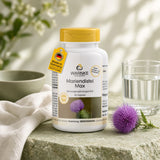Capsules de chardon-Marie Max dans un récipient blanc avec dessus jaune, 60 capsules. Placé sur une surface en pierre avec de l'eau et une fleur d'artichaut à côté.