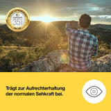 Mann i rutete skjorte som sitter på en stein og ser mot soloppgangen i et fjellandskap.