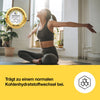 Kvinne i sporty antrekk med grå topp og tights utfører en yogaøvelse i lyst rom med planter.