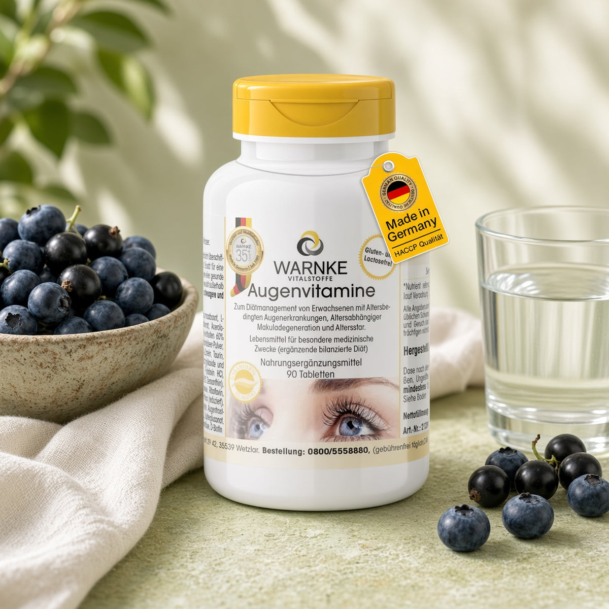 Øjenvitaminer i en hvid flaske med gul låg, 90 tabletter, ved siden af ​​blåbær og et glas vand.