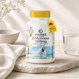 D-Mannose 1000mg tabletter i en hvid beholder med gult låg, placeret på en naturlig overflade ved siden af ​​et glas vand.