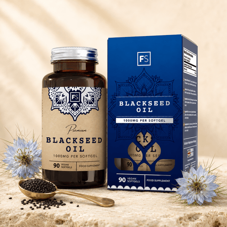 Premium black seed oil in brown glass bottle with silver cap and blue box, surrounded by black seeds and flowers.